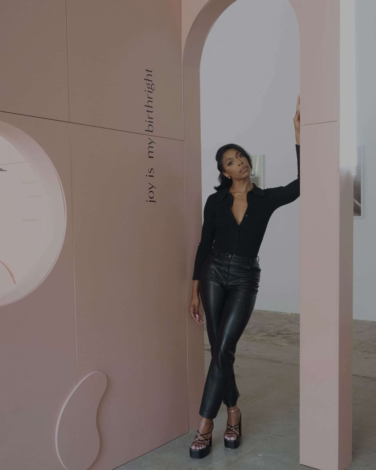 Deun Ivory standing in an arch at her exhibition, beside the words “joy is my birthright”