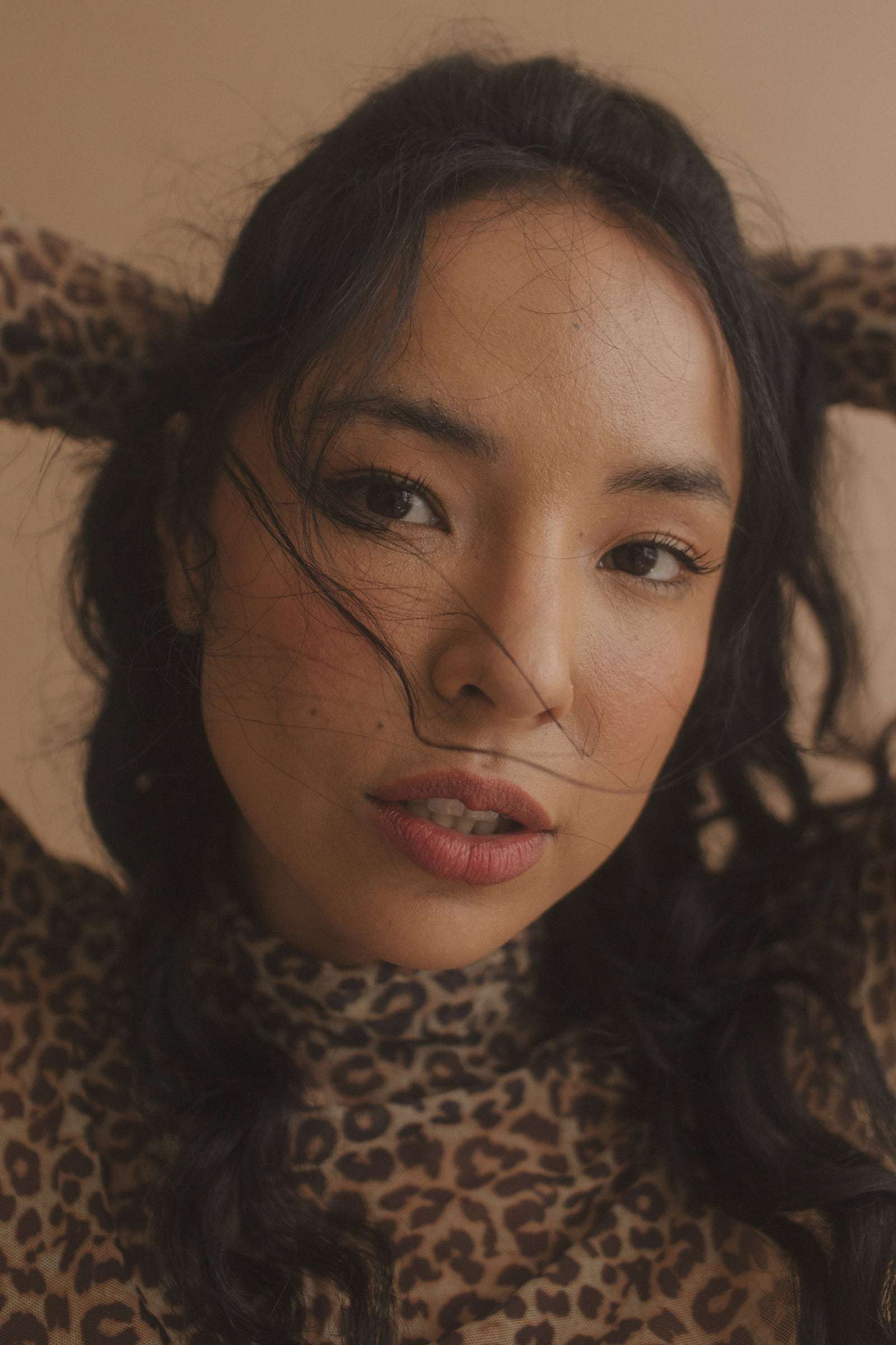 A woman with freckles and windswept hair in a leopard-print top, from Deun Ivory’s campaign for Glossier