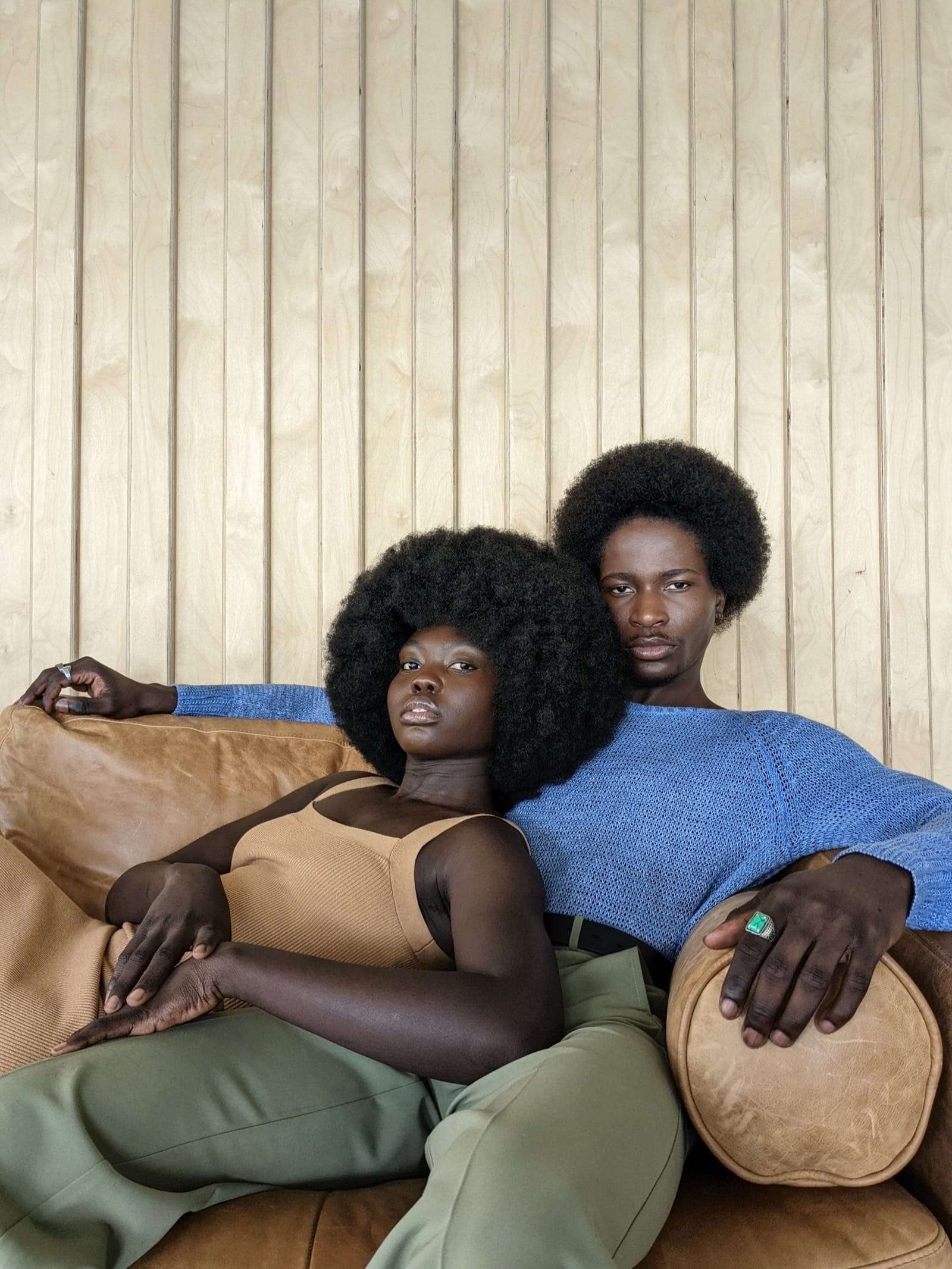 Two friends lounging on a tan leather sofa against pale wood panels, from Deun Ivory’s campaign for Google Pixel