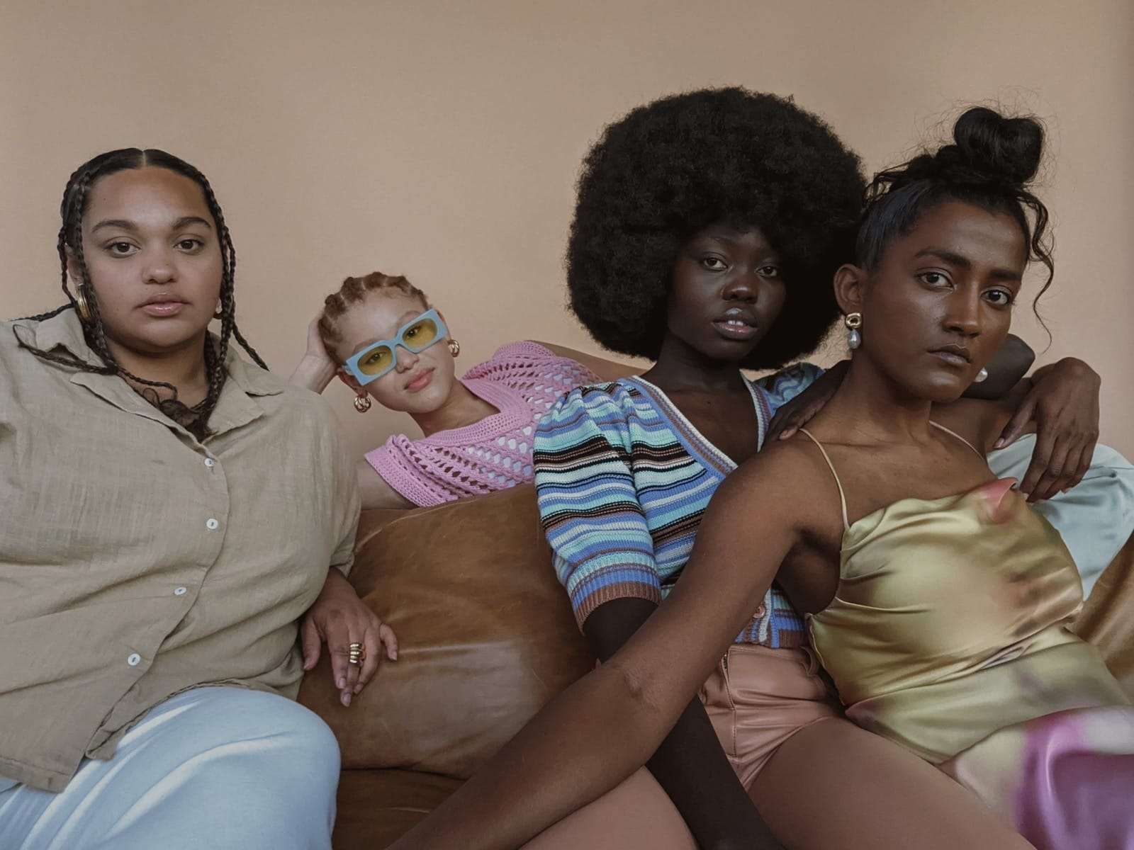 Four friends gathered close on a sofa against a blush wall, from Deun Ivory’s campaign for Google Pixel