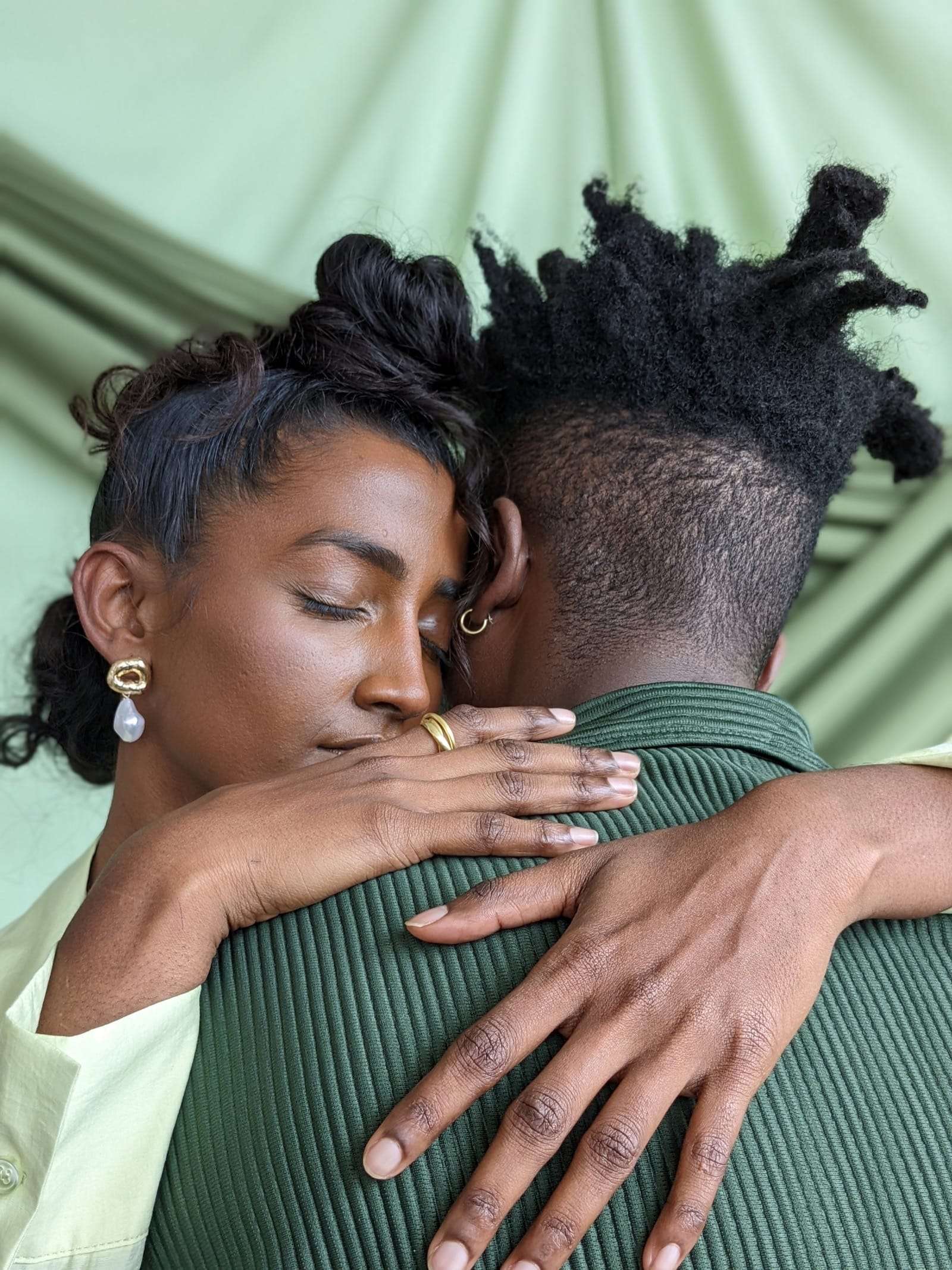 A couple holding each other, eyes closed, against a green backdrop, from Deun Ivory’s campaign for Google Pixel