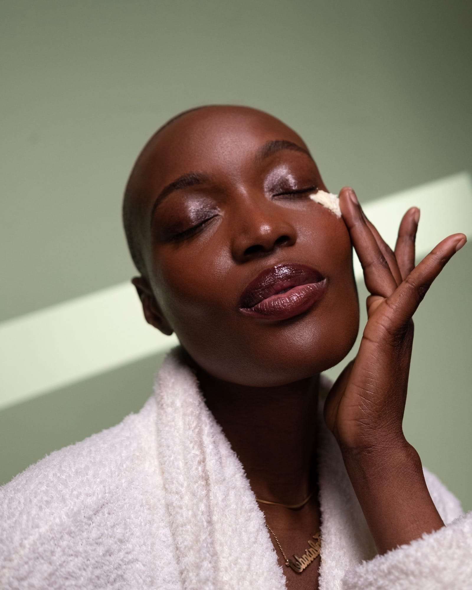 A woman in a white robe, eyes closed, touching cream to her cheek, from Deun Ivory’s campaign for Hanahana Beauty at ULTA