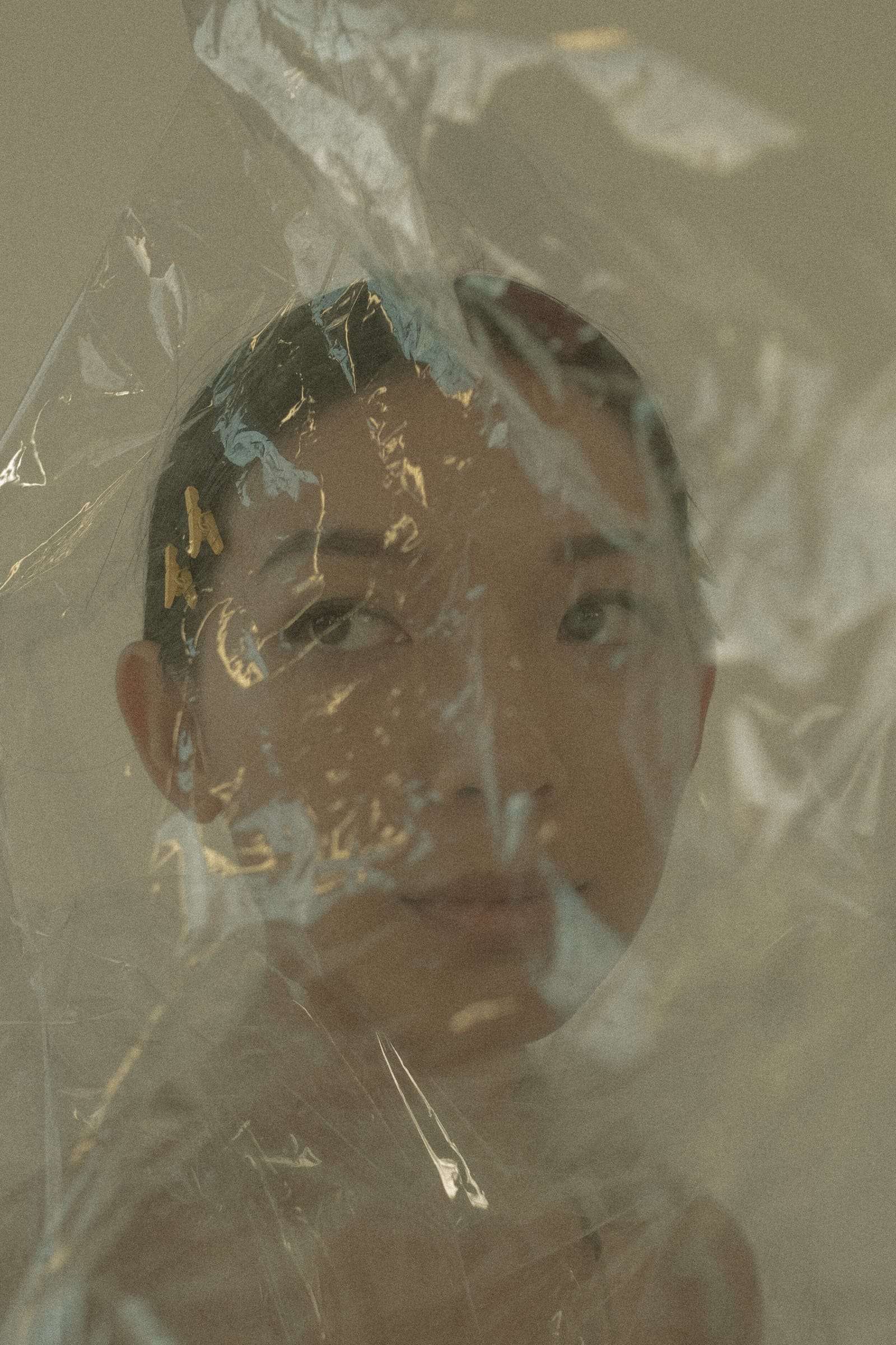 A woman’s face seen through crumpled clear plastic, from Deun Ivory’s campaign for Honeynsilk