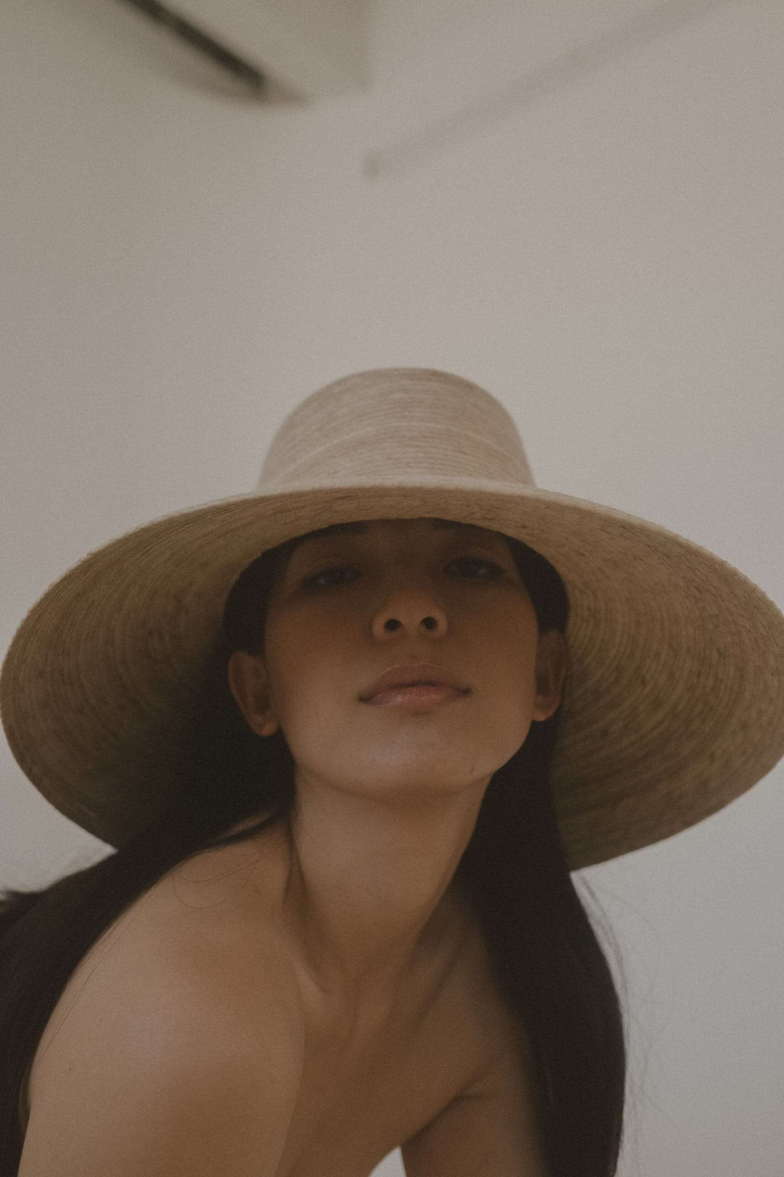 A woman in a wide straw hat looking up at the camera, from Deun Ivory’s campaign for Honeynsilk