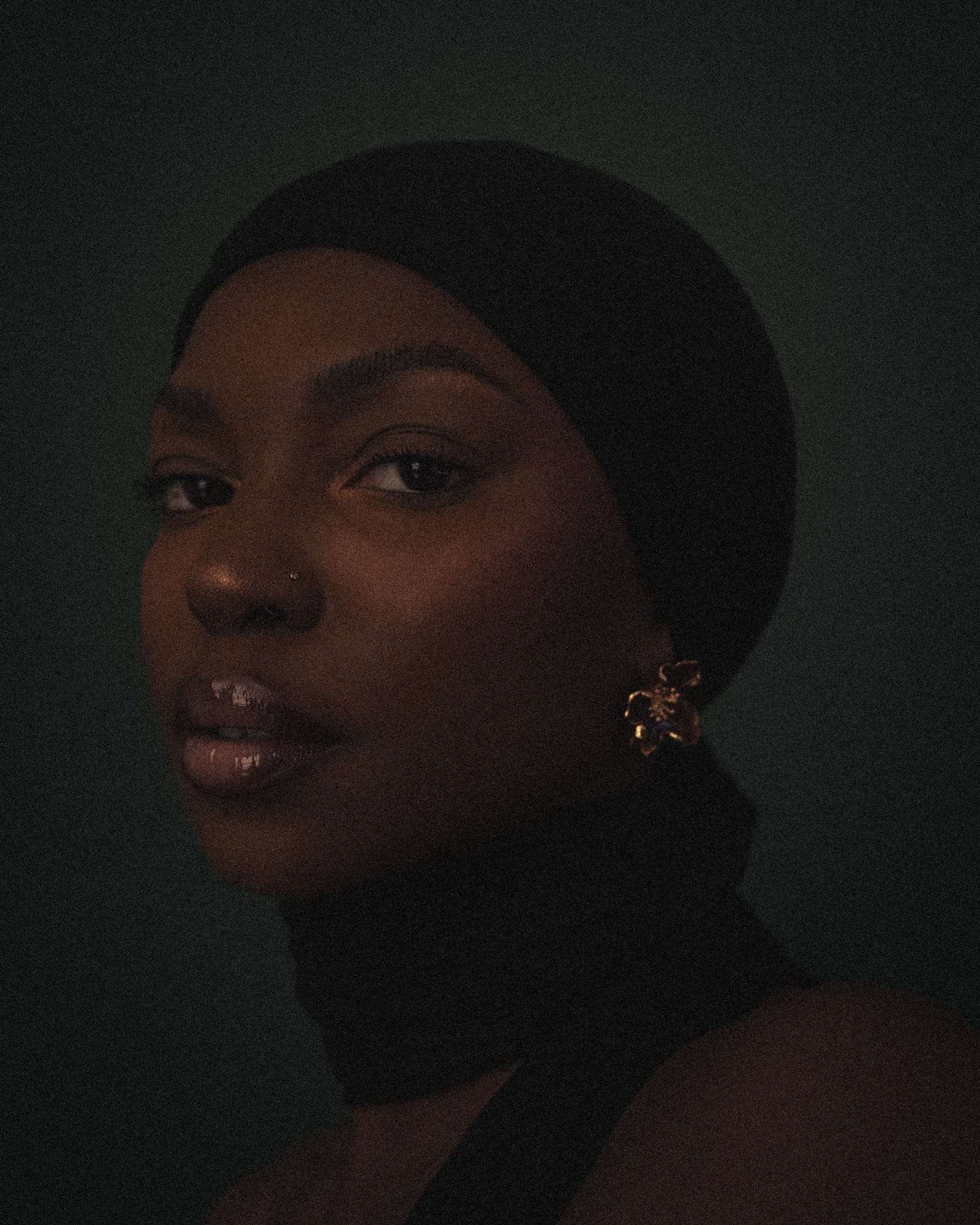 Kristen in a black head wrap and gold earring, in low light, from Deun Ivory’s portraits of Kristen for VSCO