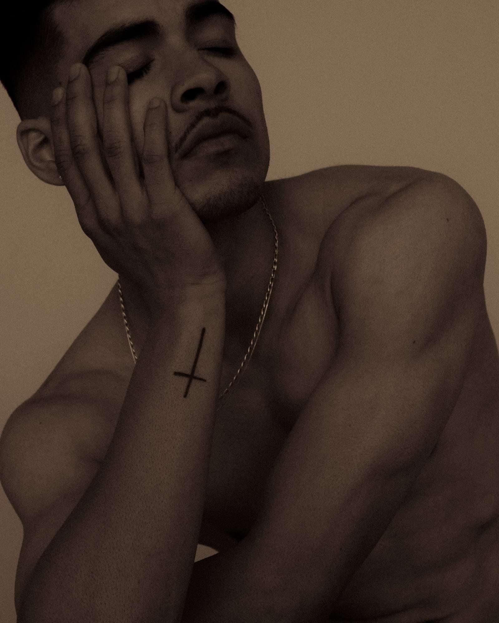A man with his eyes closed and a hand on his cheek, in warm light, from Deun Ivory’s 2024 campaign for Youth To The People