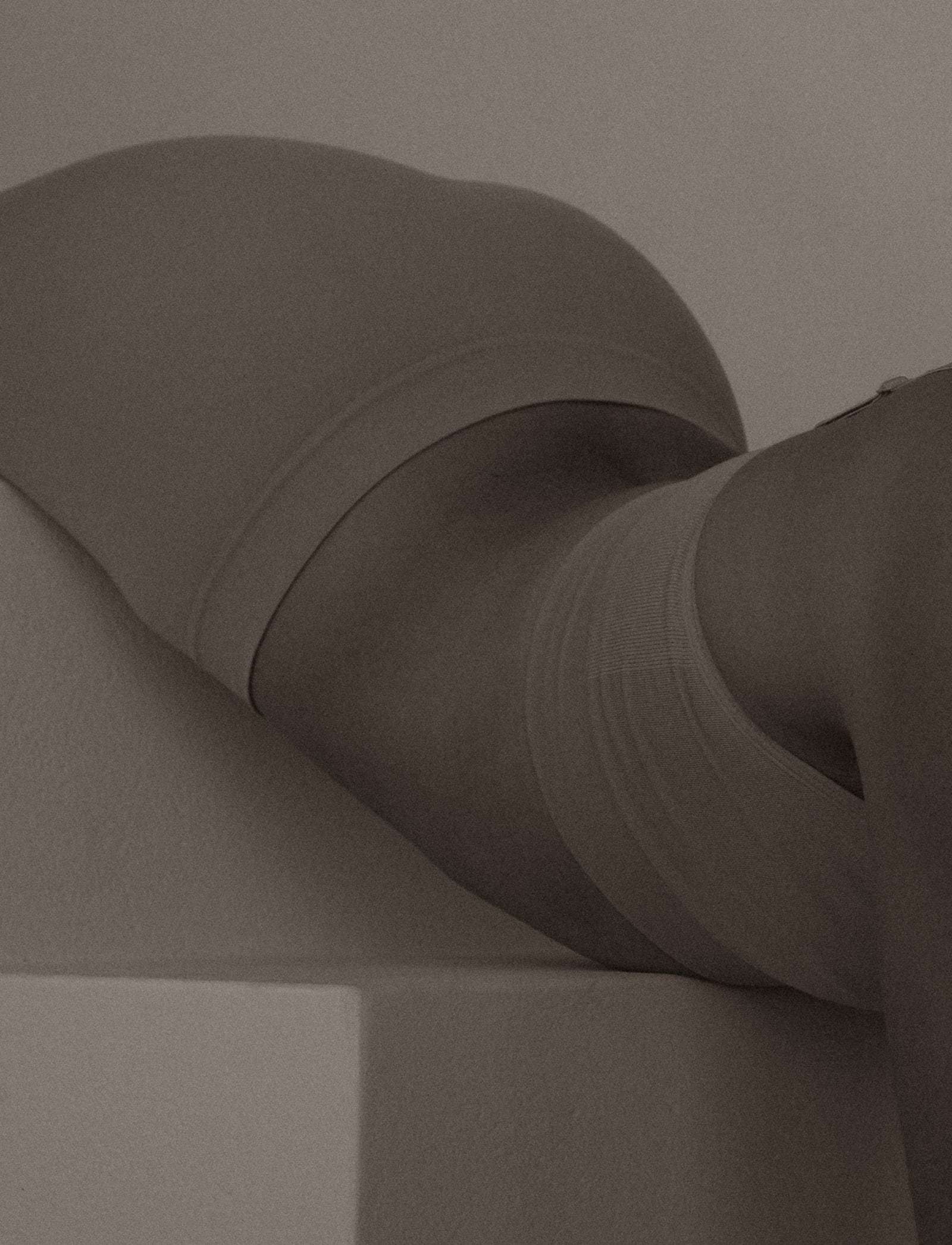 A close crop of a body resting on a white block, in soft brown light, from Deun Ivory’s 2024 campaign for Youth To The People