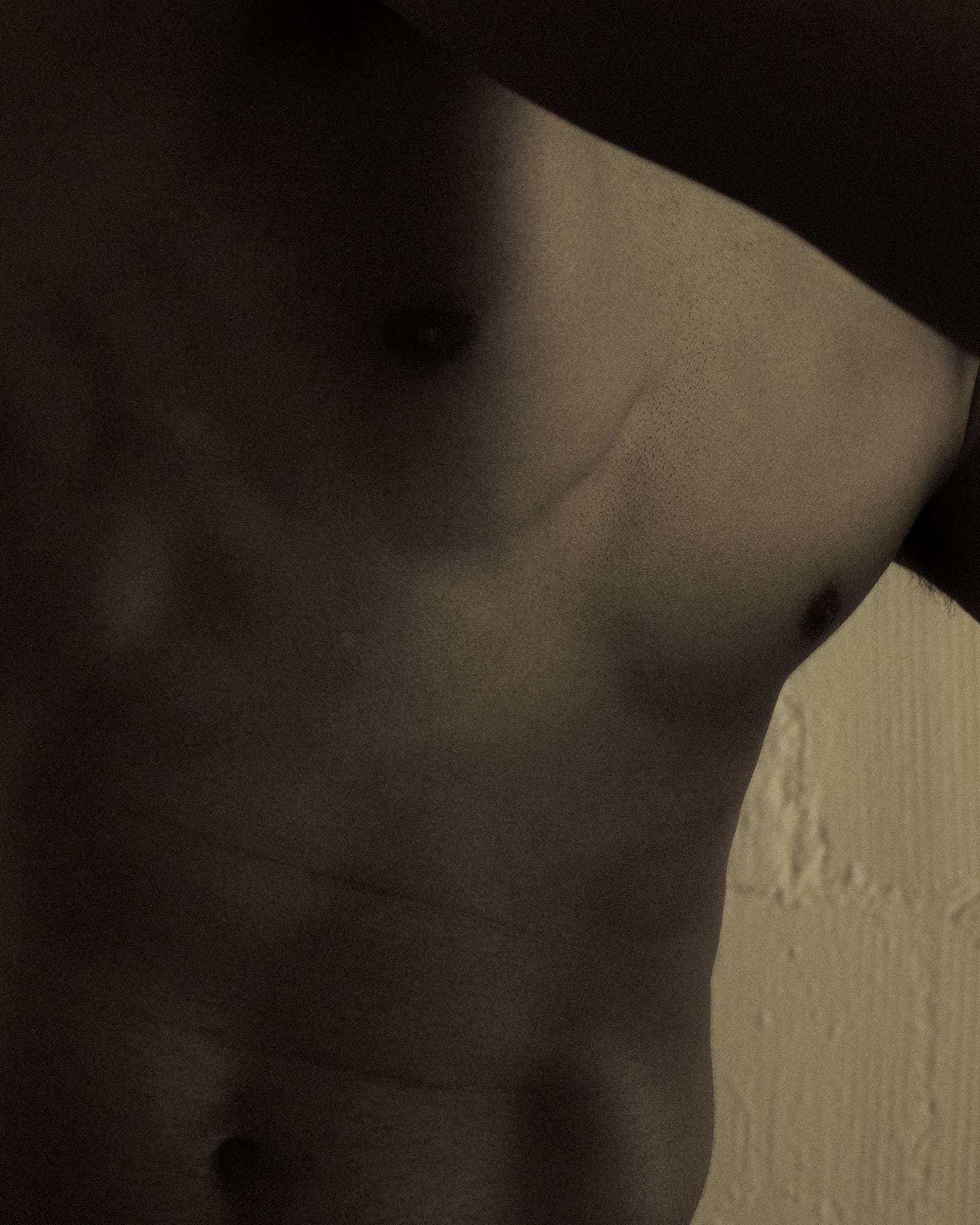 A close crop of a bare chest and shoulder in warm light, from Deun Ivory’s 2024 campaign for Youth To The People